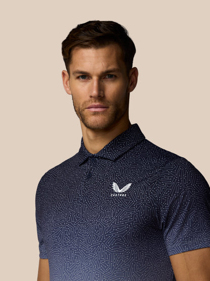 Man wearing a navy patterned polo shirt with a logo on a beige background