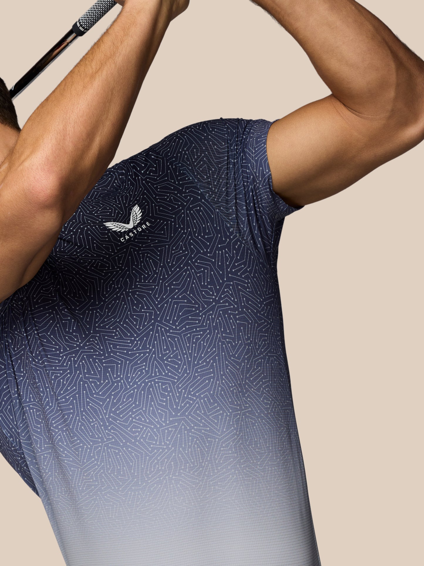 Person wearing a navy blue athletic shirt with a logo on a beige background