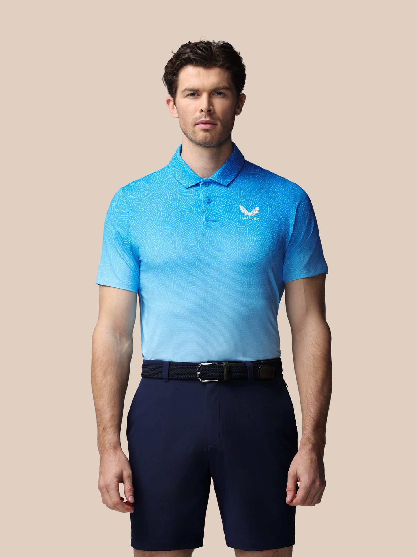 Man wearing a light blue polo shirt with a Castore logo on a beige background