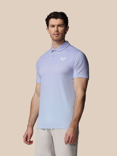 Man wearing a light blue polo shirt with a logo on a beige background