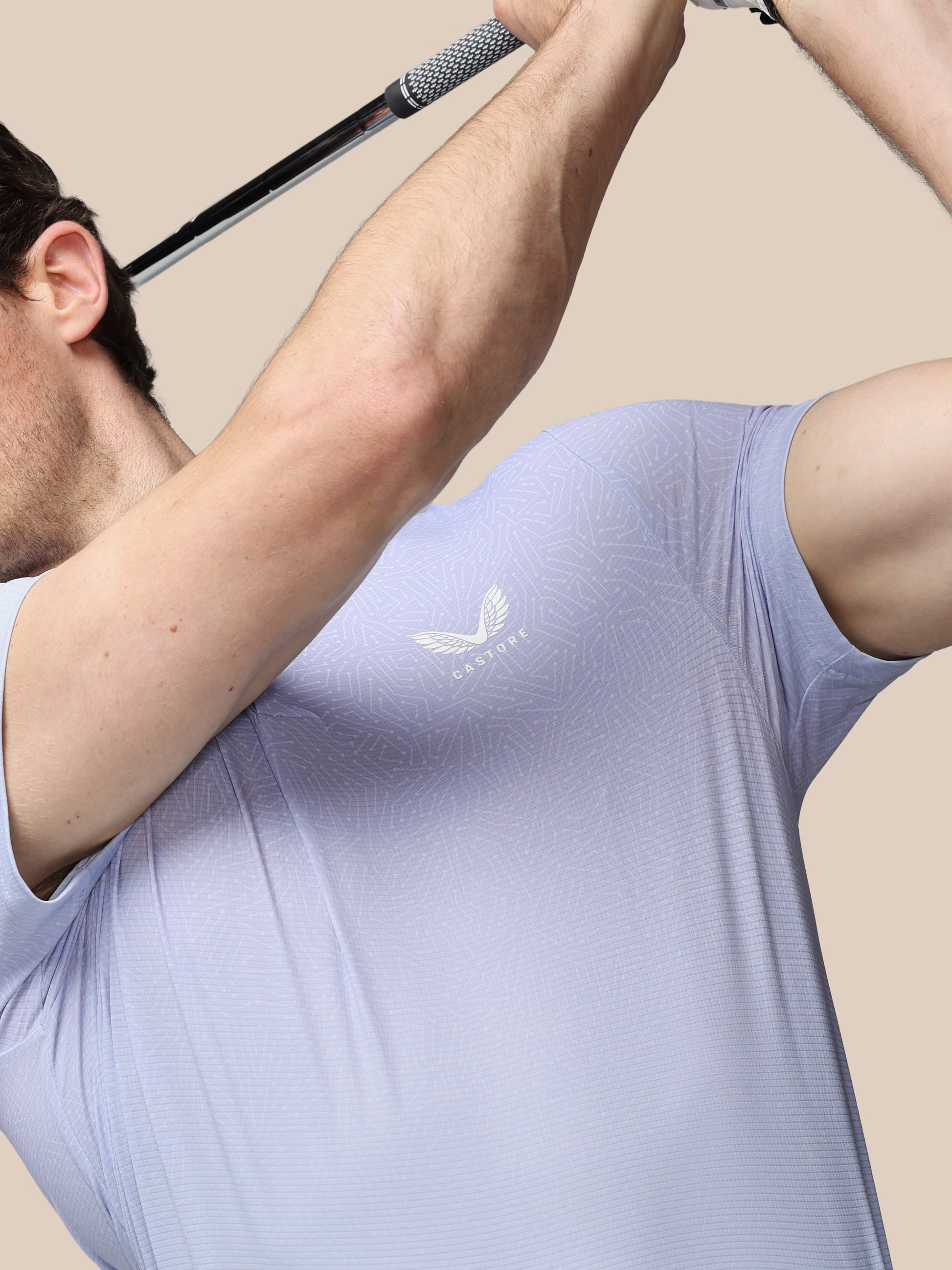 Person wearing a light purple athletic shirt with a logo, holding a golf club.