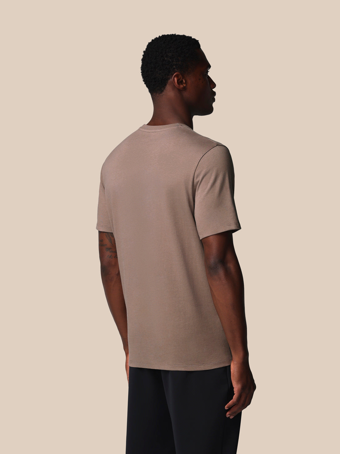 Man wearing a beige t-shirt against a beige background