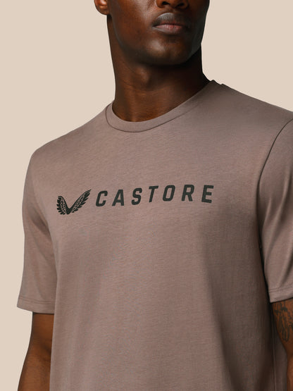 Man wearing a brown t-shirt with 'CASTORE' logo on a beige background