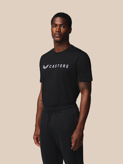 Man wearing a black 'Castore' t-shirt against a beige background
