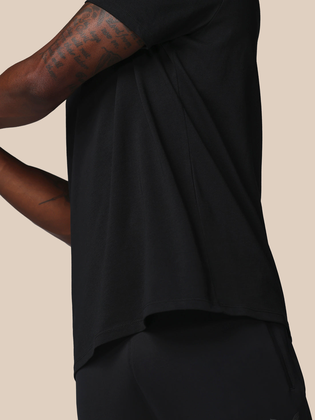 Person wearing a black sleeveless top on a beige background