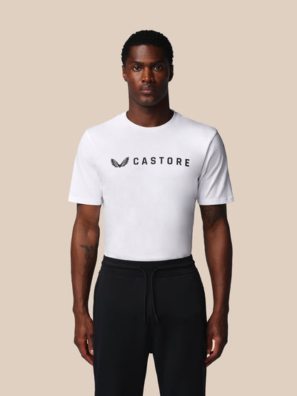 Person wearing a white t-shirt with 'Castore' logo on a beige background