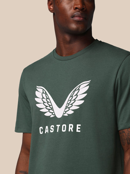 Man wearing a green t-shirt with a white logo and 'CASTORE' text on a beige background