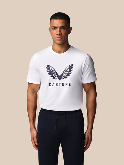 Man wearing a white t-shirt with a logo and text on a beige background