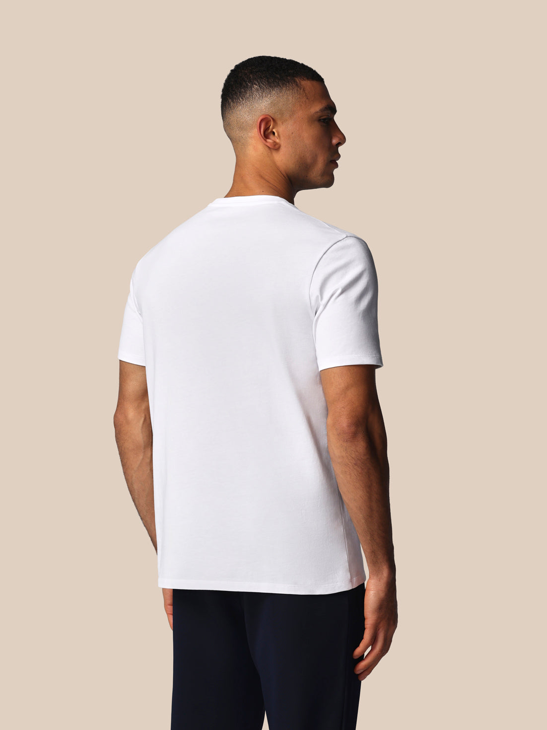 Man wearing a white t-shirt against a beige background