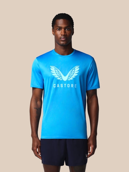Man wearing a blue Castore t-shirt with a logo on a beige background