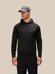 Male model in black Reiss x Castore Flex Hoodie with hood down and a grey cap
