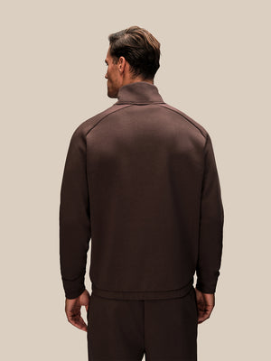 Back view of brown oversized Reiss x Castore 1/4 zip sweatshirt on a model with a high collar.