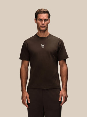 Man wearing brown oversized Reiss x Castore T shirt with small white chest logo.