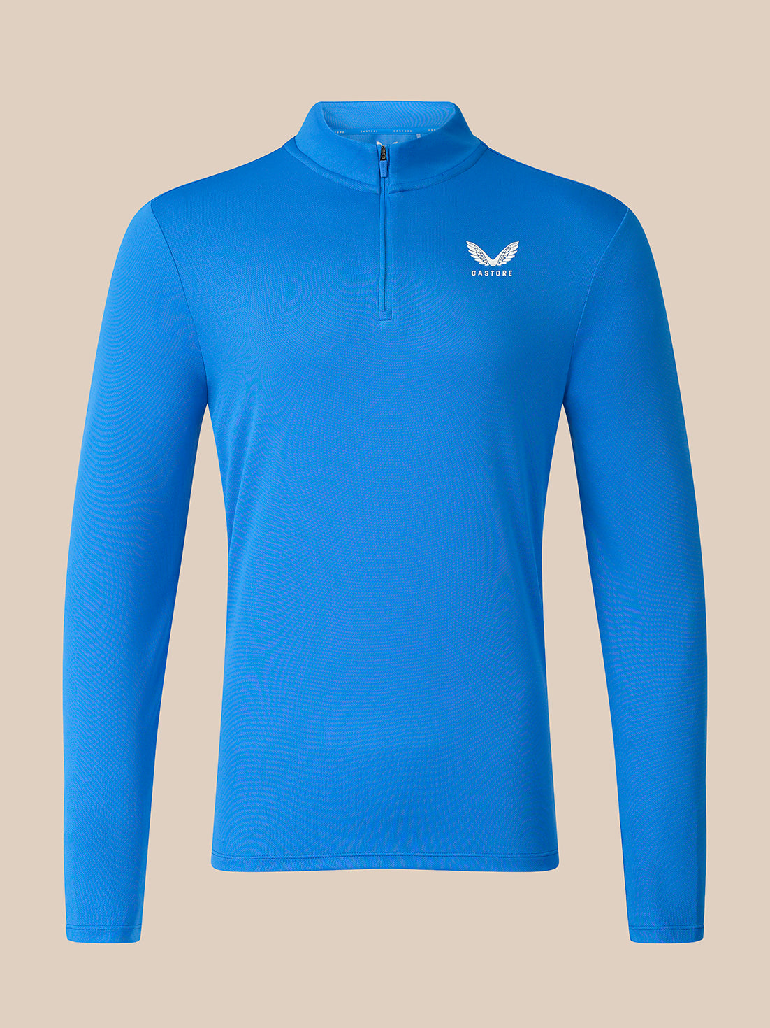 A bright blue long-sleeve quarter-zip pullover top with a small white wing logo and the word 'CASTORE' on the left chest, displayed on a solid beige background.