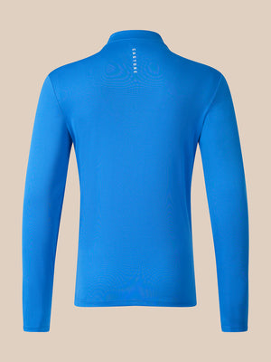 A bright blue long-sleeve athletic top shown from the back, featuring a mock neck and a small vertical white 'CaSTORE' logo printed at the center back, set against a solid beige background.