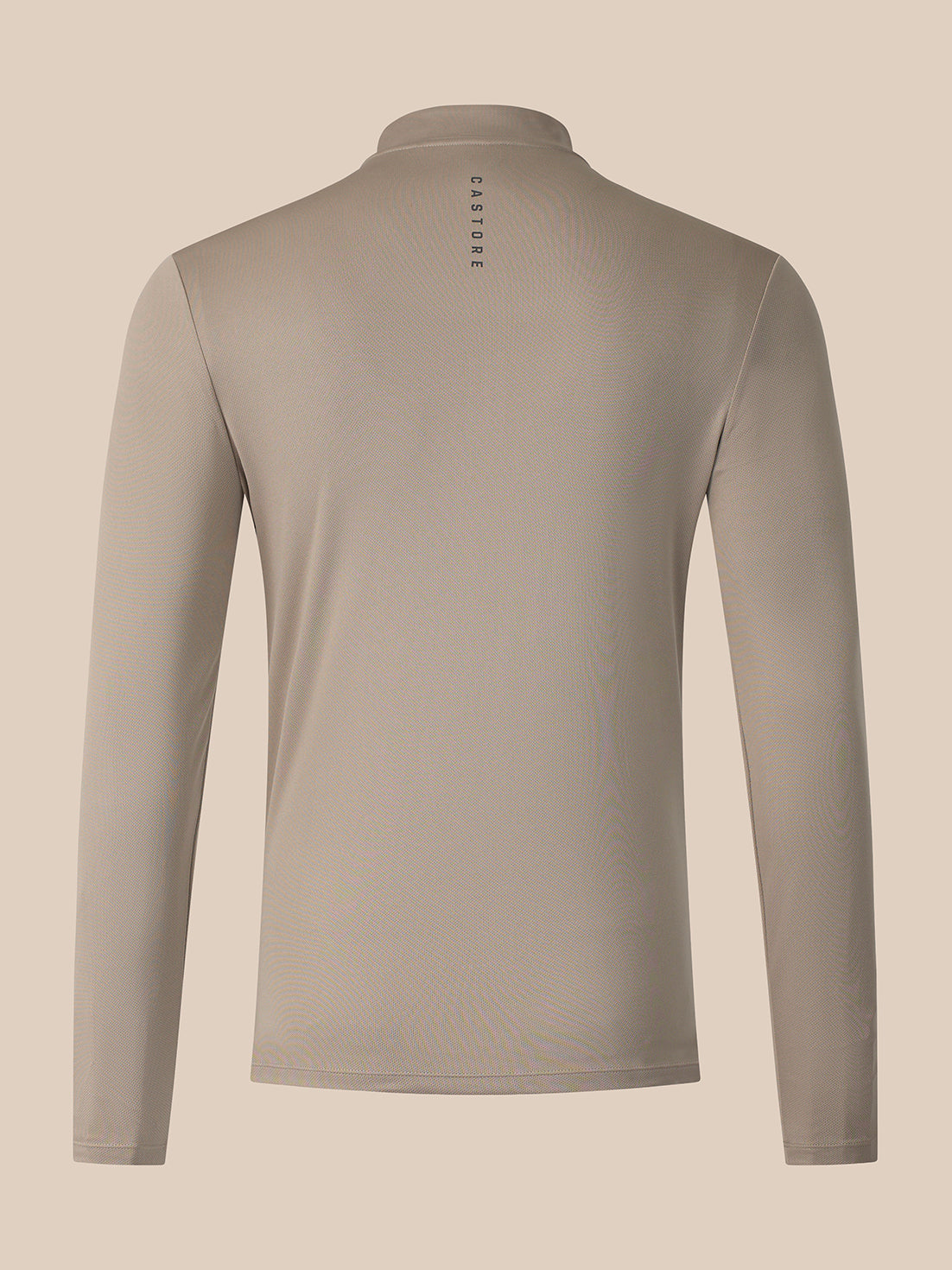 A long-sleeve athletic top shown from the back, featuring a stand-up collar and a small vertical 'CASTORE' logo printed in black near the center of the neck. The garment is a solid taupe color, displayed on a clean, solid, warm beige background.