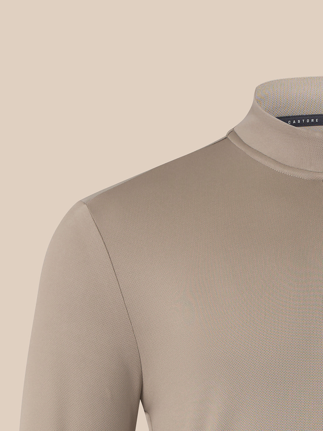 Close-up of a beige knit mock neck sweater on a mannequin against a solid beige background.