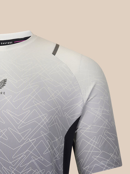 Close-up of a short-sleeve athletic jersey in white and light gray with an abstract line pattern, featuring a dark gray shoulder accent and a black Castore neck label.