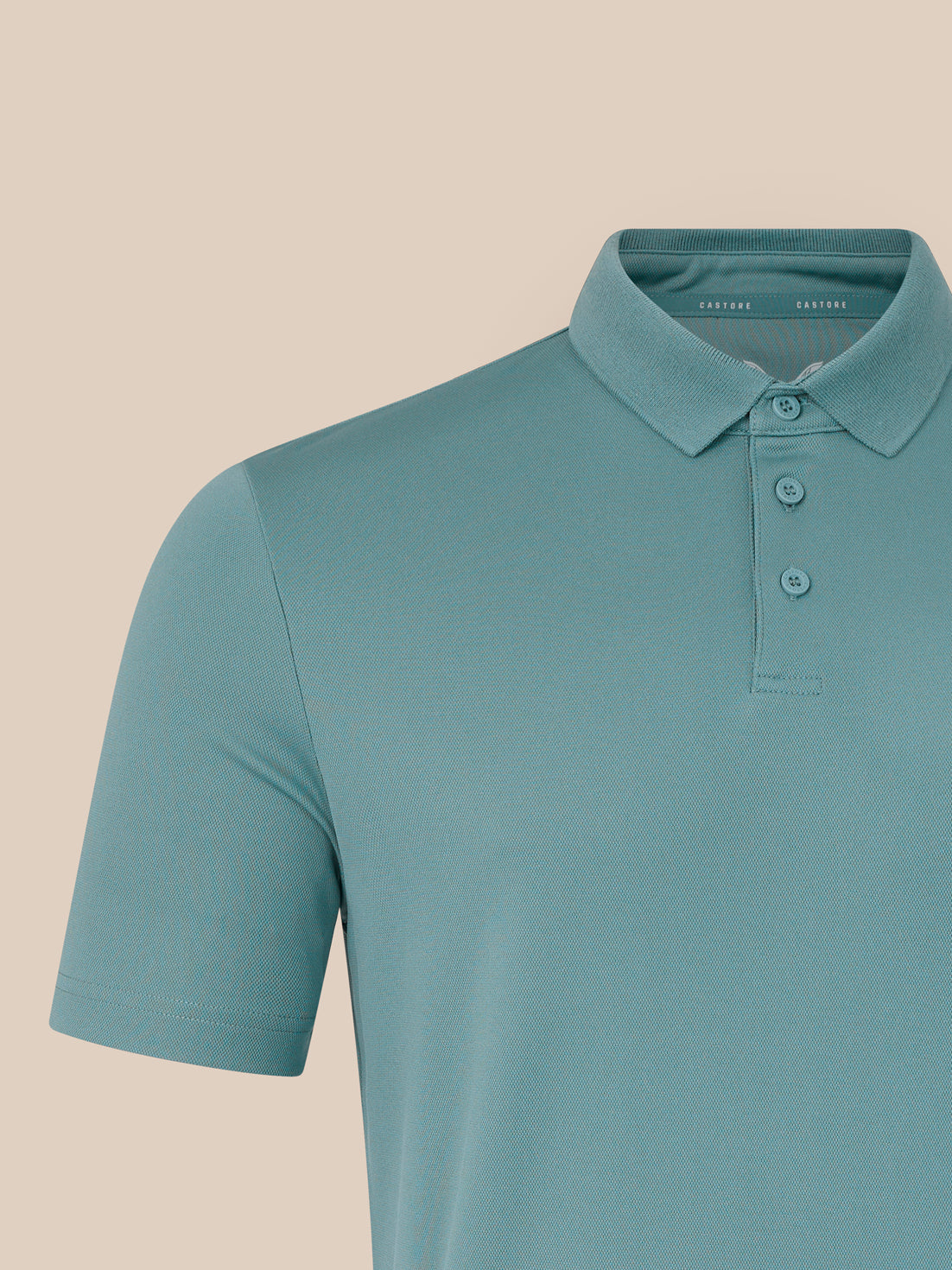 Teal polo shirt on a beige background