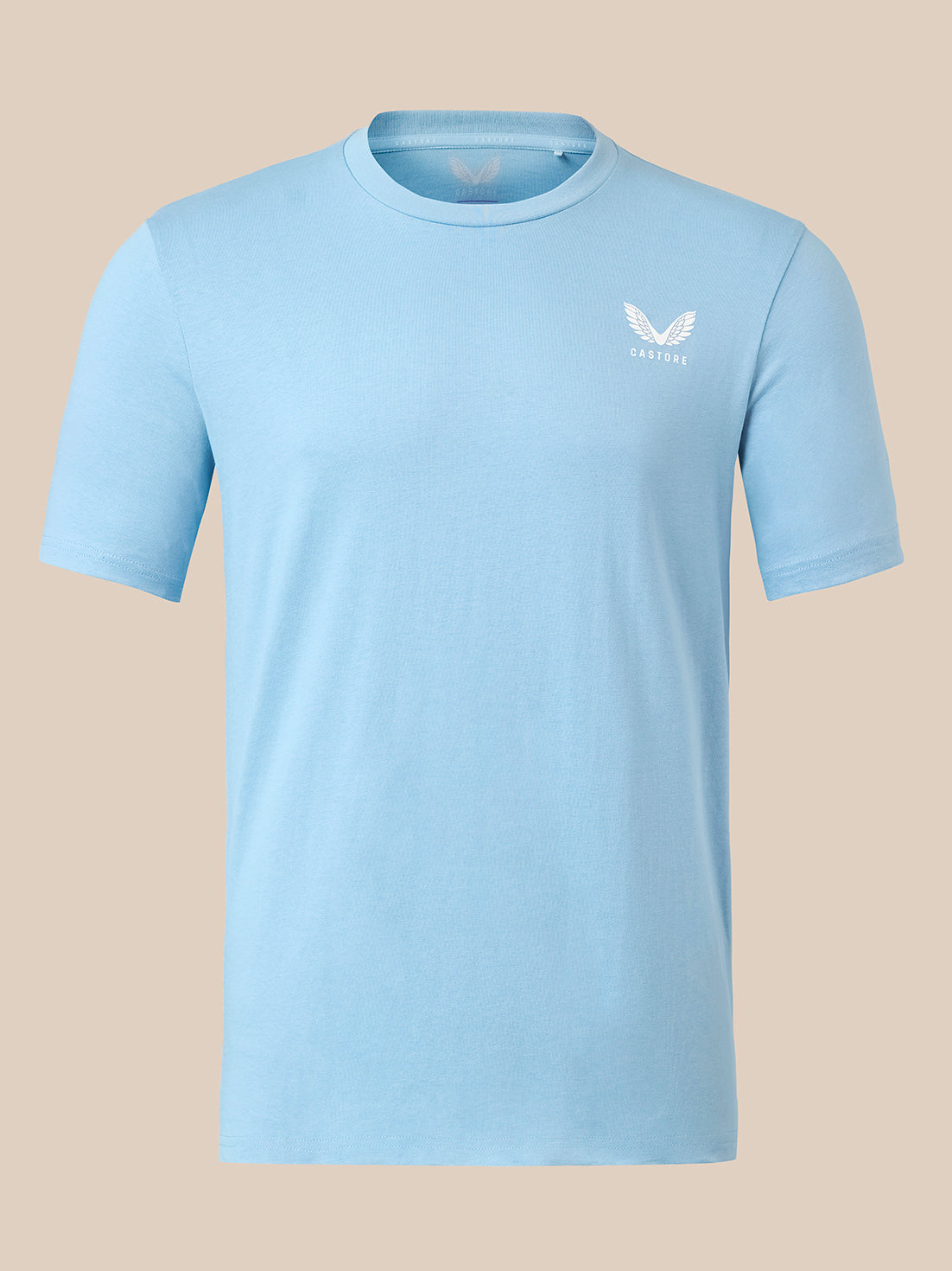 A light blue short-sleeve crewneck t-shirt with a small white winged logo on the left chest, displayed on a solid beige background.