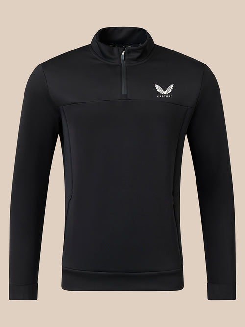 A black long-sleeve quarter-zip pullover with a small white winged logo and the brand name 'CASTORE' on the left chest, displayed on a solid beige background.