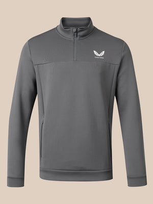A dark gray long-sleeve quarter-zip pullover sweatshirt with a white winged logo on the left chest reading 'CASTORE', displayed against a solid beige background.