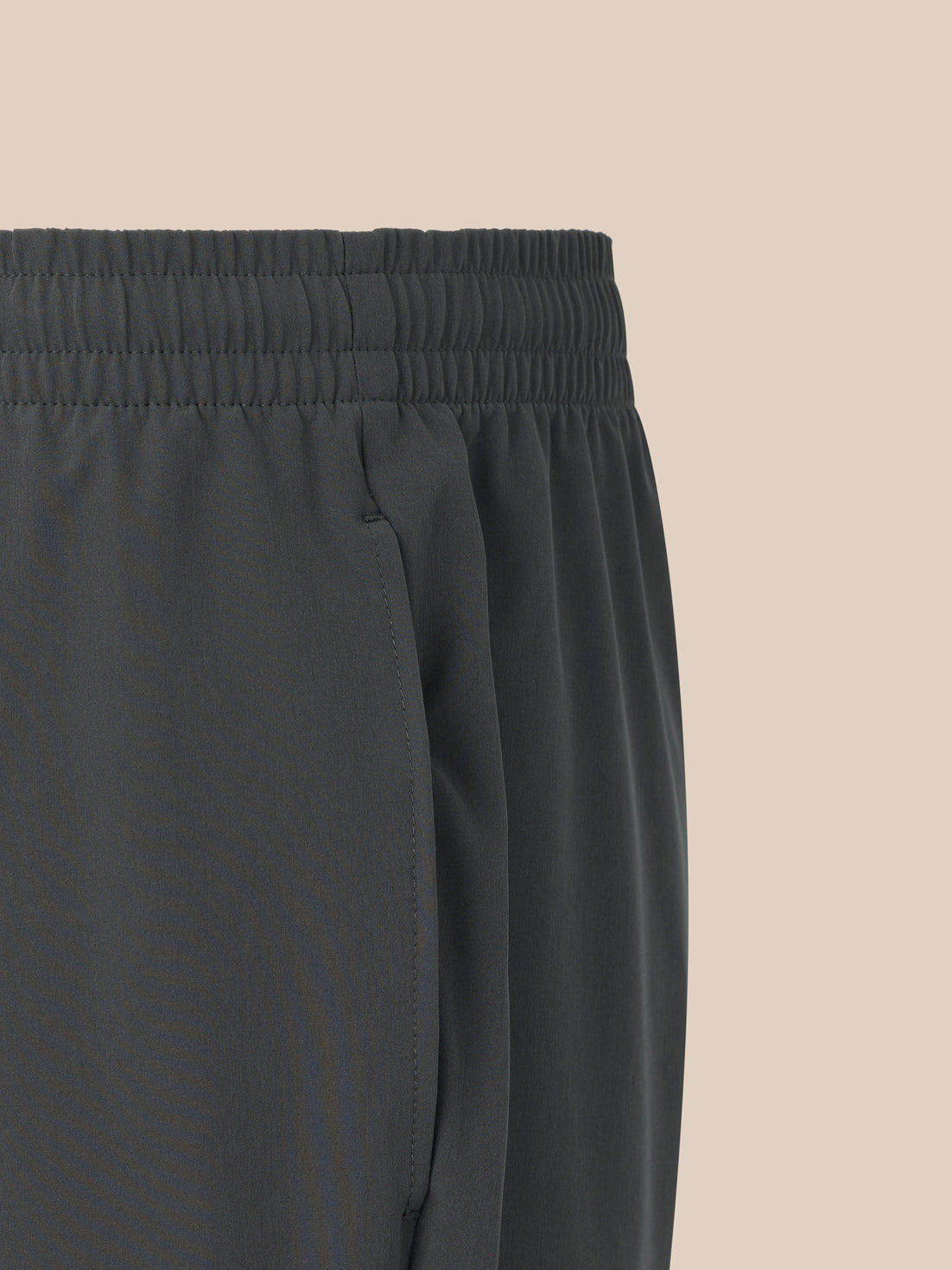 Dark gray pants with an elastic waistband on a beige background