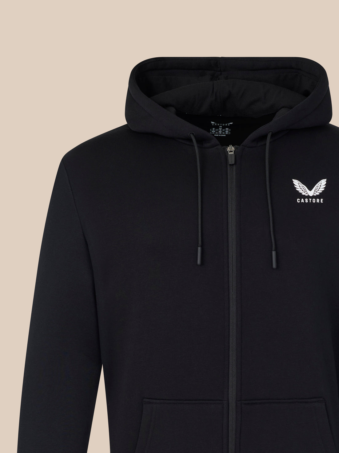 Black hoodie with a logo on the chest against a beige background