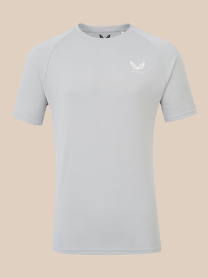 A light gray short-sleeve athletic t-shirt with a small white wing logo and the brand name 'CASTORE' printed on the left chest, displayed against a solid beige background.