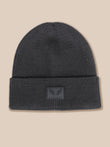A dark gray ribbed knit beanie hat with a folded cuff, featuring a small rectangular embossed patch on the front with a winged logo and the brand name CASTORE.