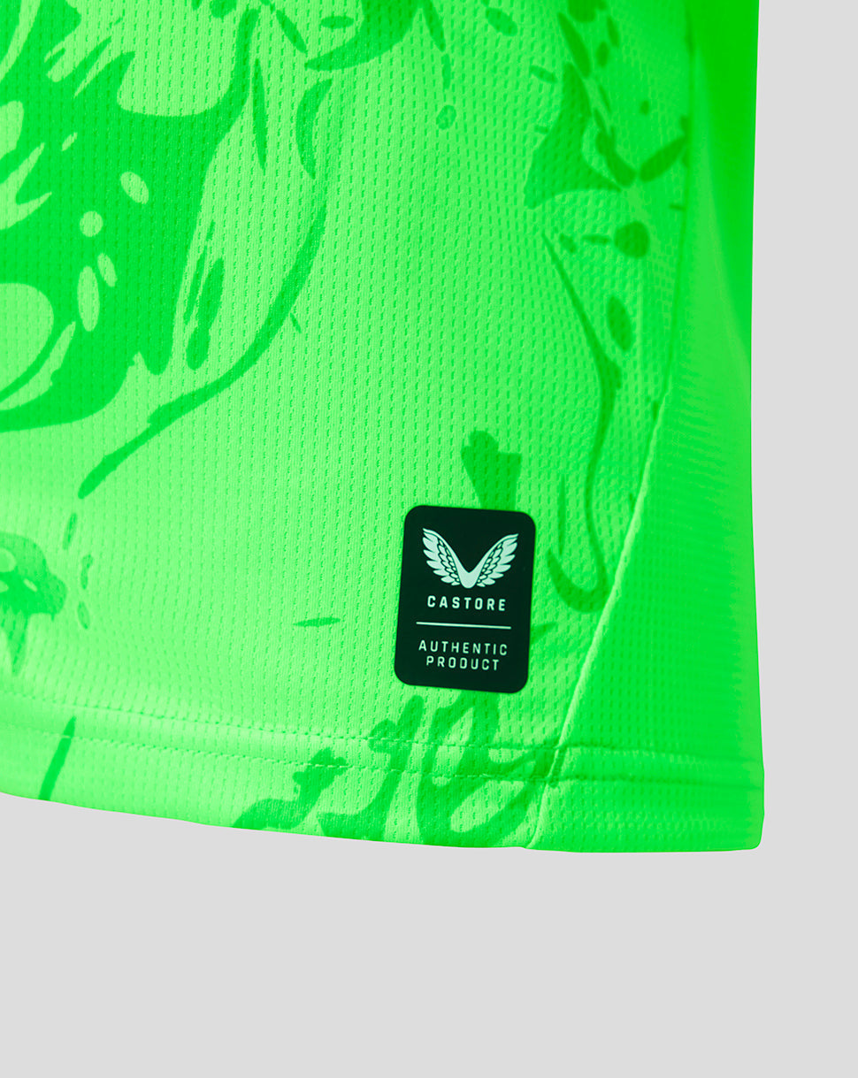 Close-up of a bright neon green athletic jersey with a subtle tonal abstract pattern and a black Castore Authentic Product label on the lower front.
