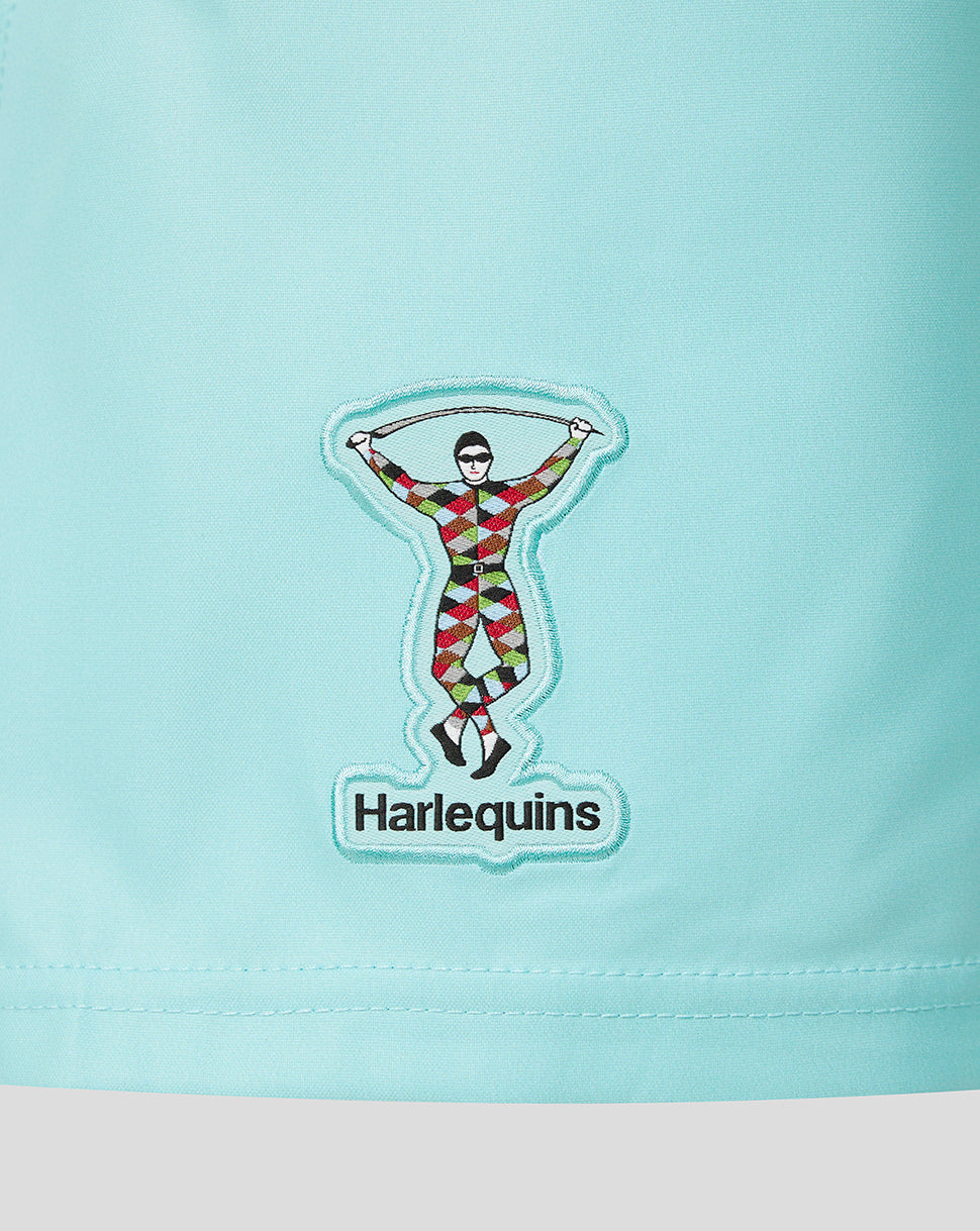 A close-up of a light aqua blue garment featuring an embroidered patch of a harlequin figure and the word 'Harlequins' below it.