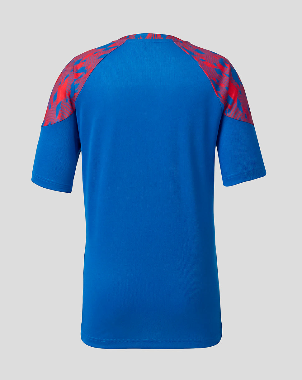A blue short-sleeve athletic jersey shown from the back, featuring a red and blue abstract patterned yoke on the shoulders, set against a solid light gray background.