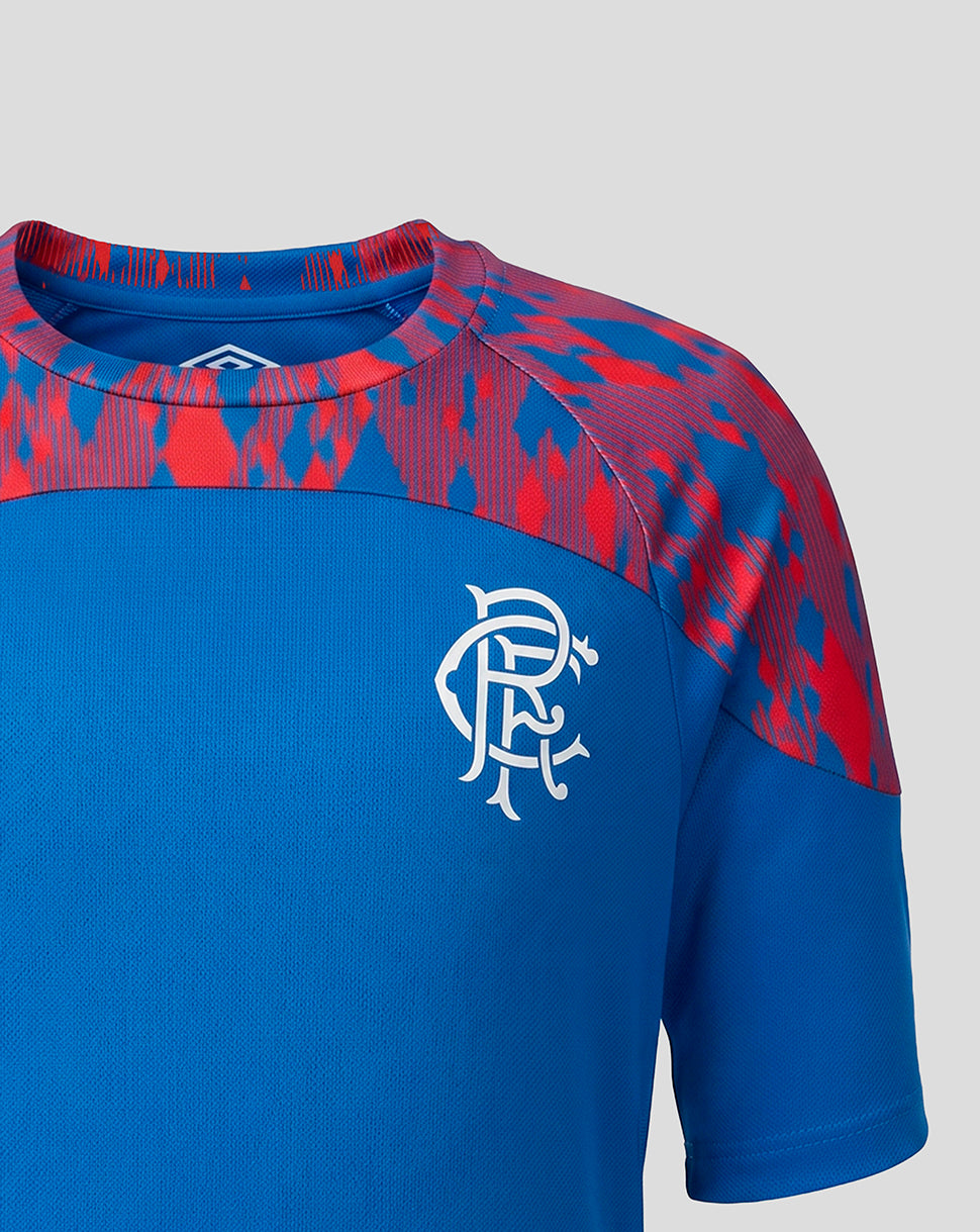 A close-up of a short-sleeve athletic jersey in royal blue with a red and blue patterned yoke and shoulder area, featuring a white Rangers FC crest on the chest.