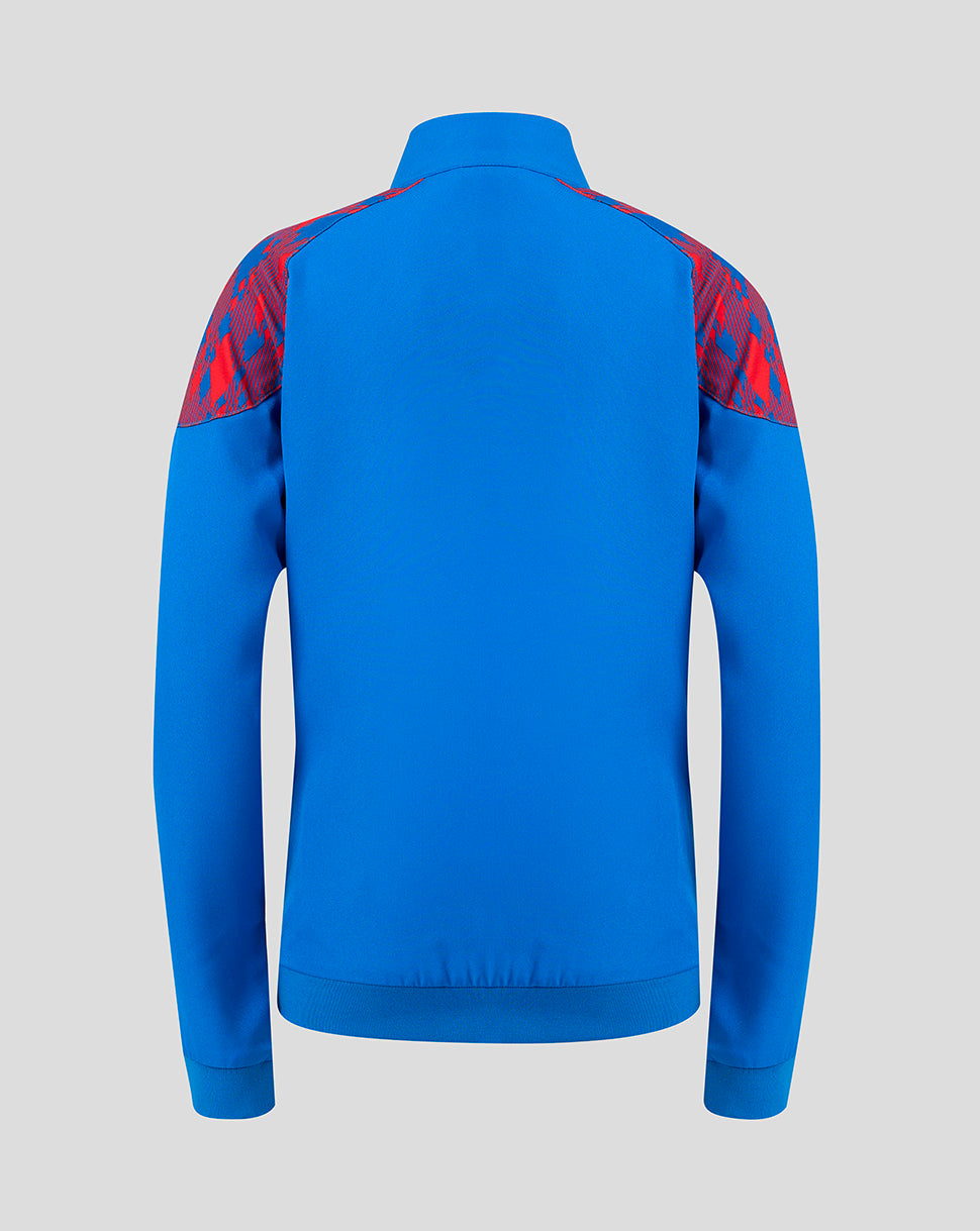 A bright blue long-sleeve athletic jacket shown from the back, featuring red patterned shoulder panels, on a solid light gray background.