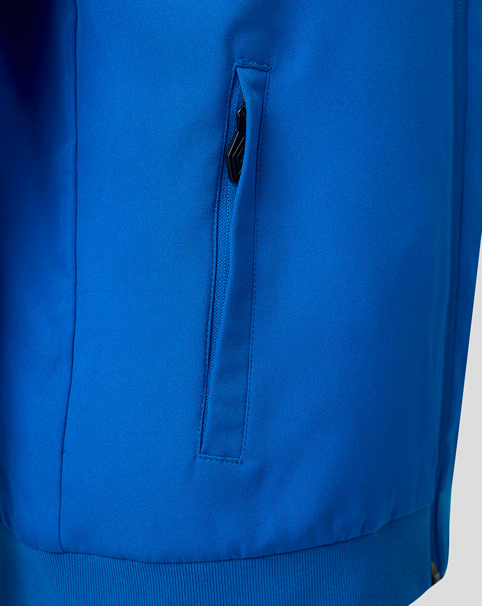 Close-up of a bright blue jacket or sweatshirt showing a vertical zippered pocket with a black zipper pull and ribbed cuffs.
