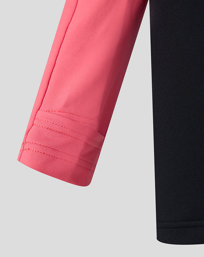 Close-up of pink sleeve and black pants on a light gray background