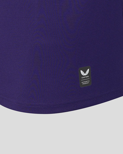 Close-up of a purple garment with a brand logo on a light gray background