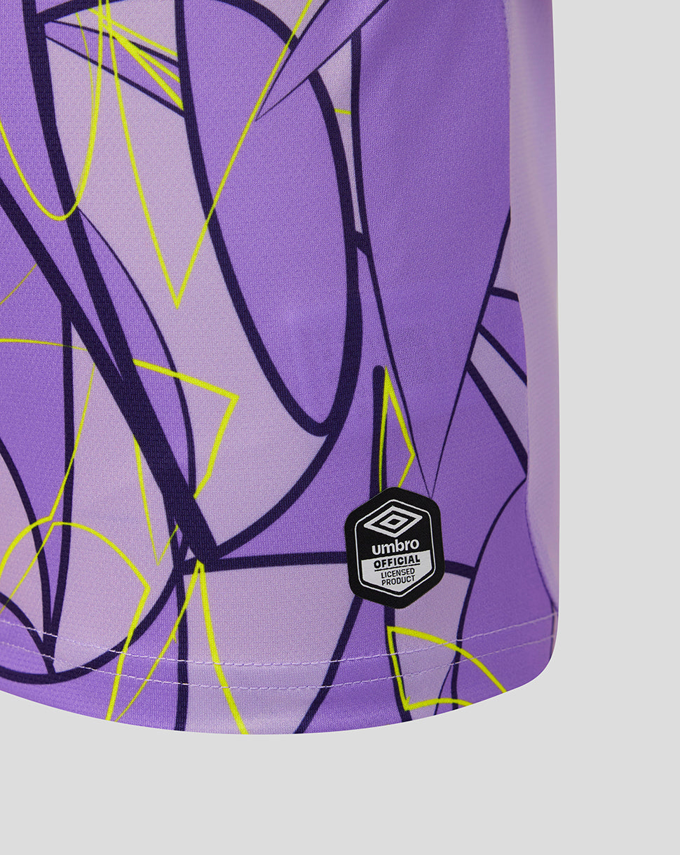 Close-up of a purple athletic garment with an abstract black and neon yellow line pattern, featuring a black Umbro logo patch near the bottom.