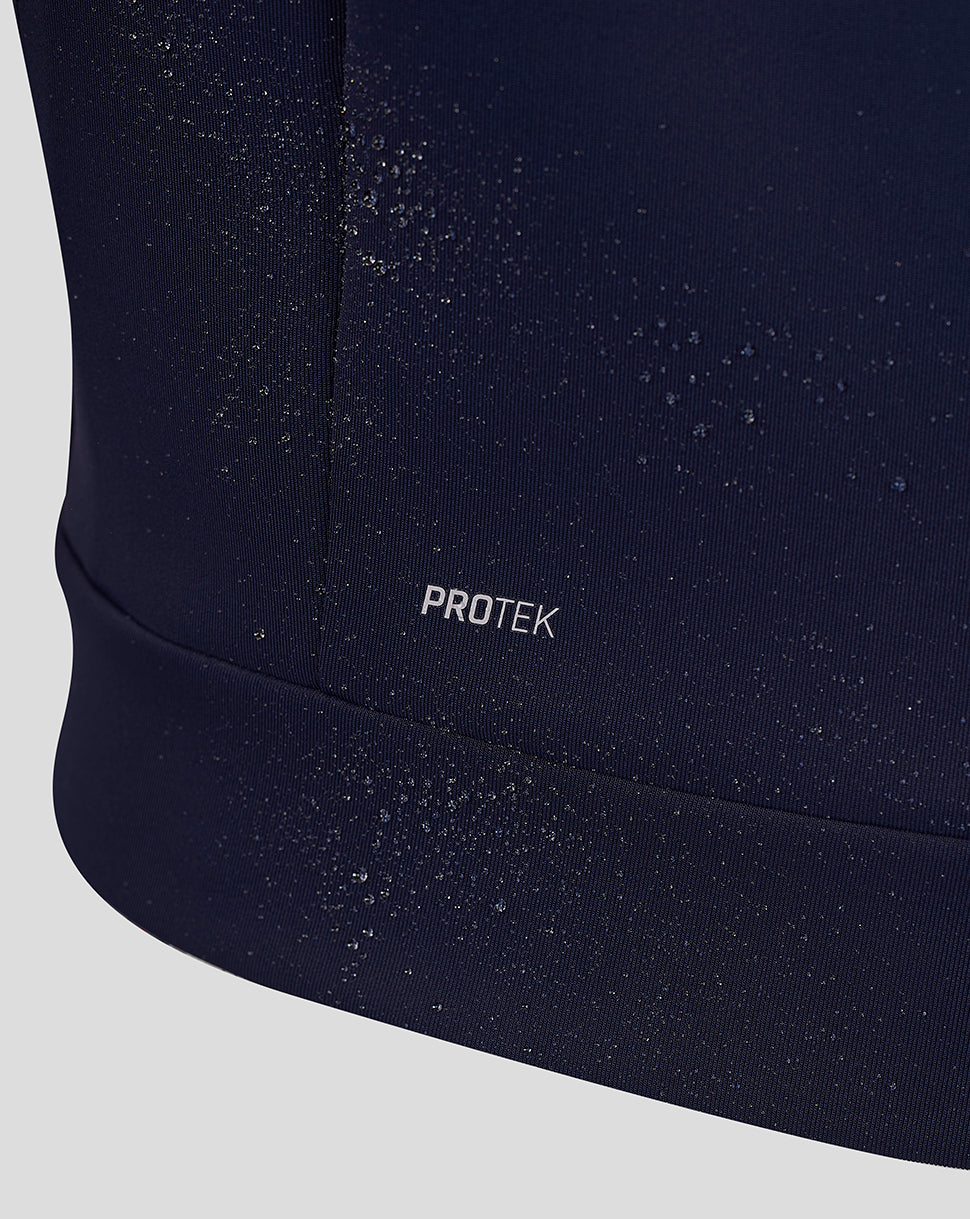 Close up of navy Travel Hoodie fabric showing water beads and the Protek branding at the hem.