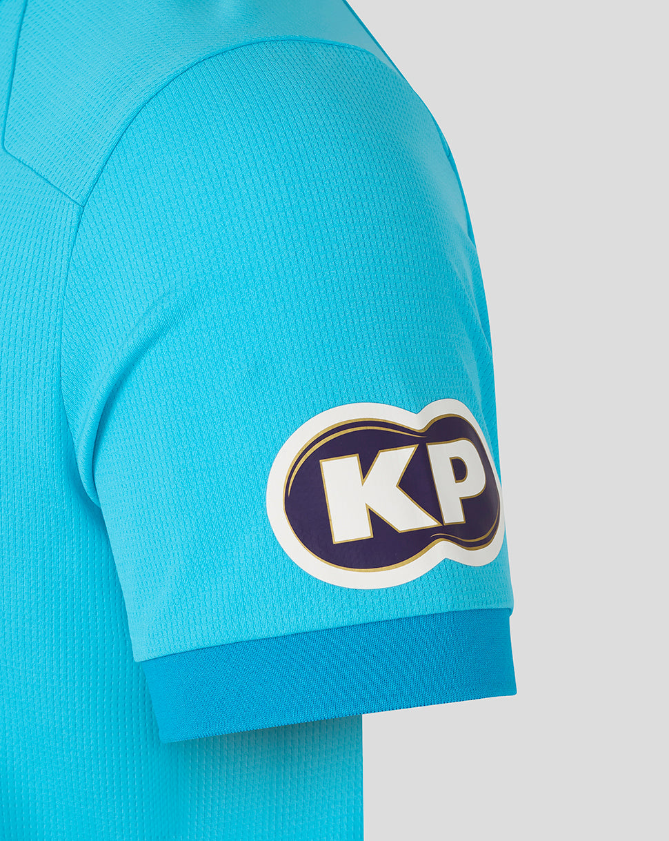 Close-up of a turquoise sports jersey with a logo on the sleeve against a white background