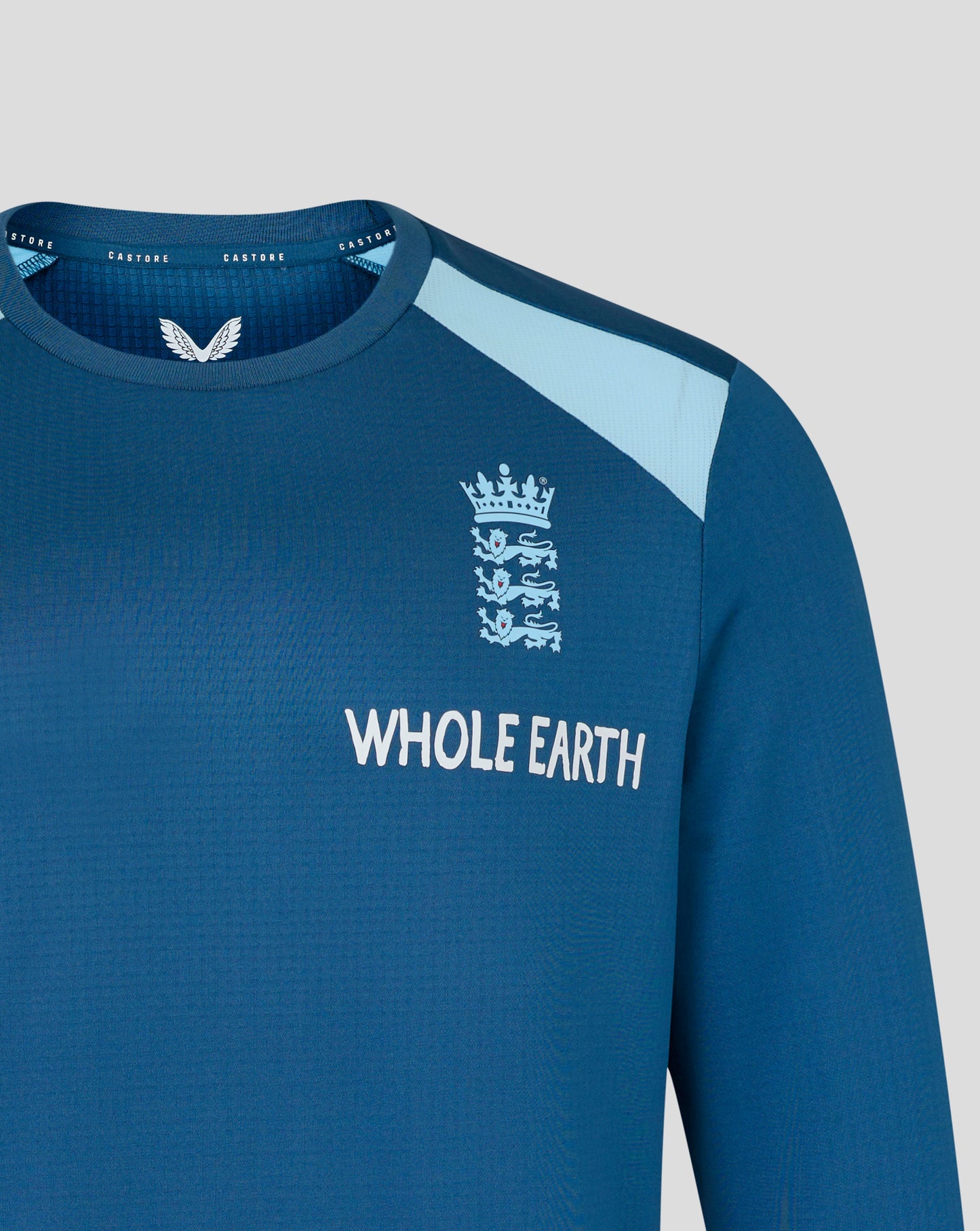 Blue long-sleeve shirt with 'Whole Earth' branding and a logo on a light gray background