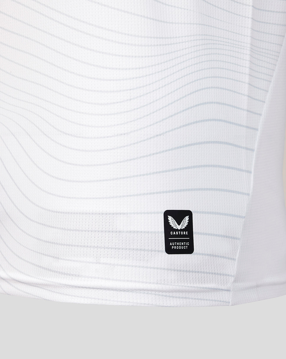 Close-up of a white textured shirt with a brand logo on a light gray background