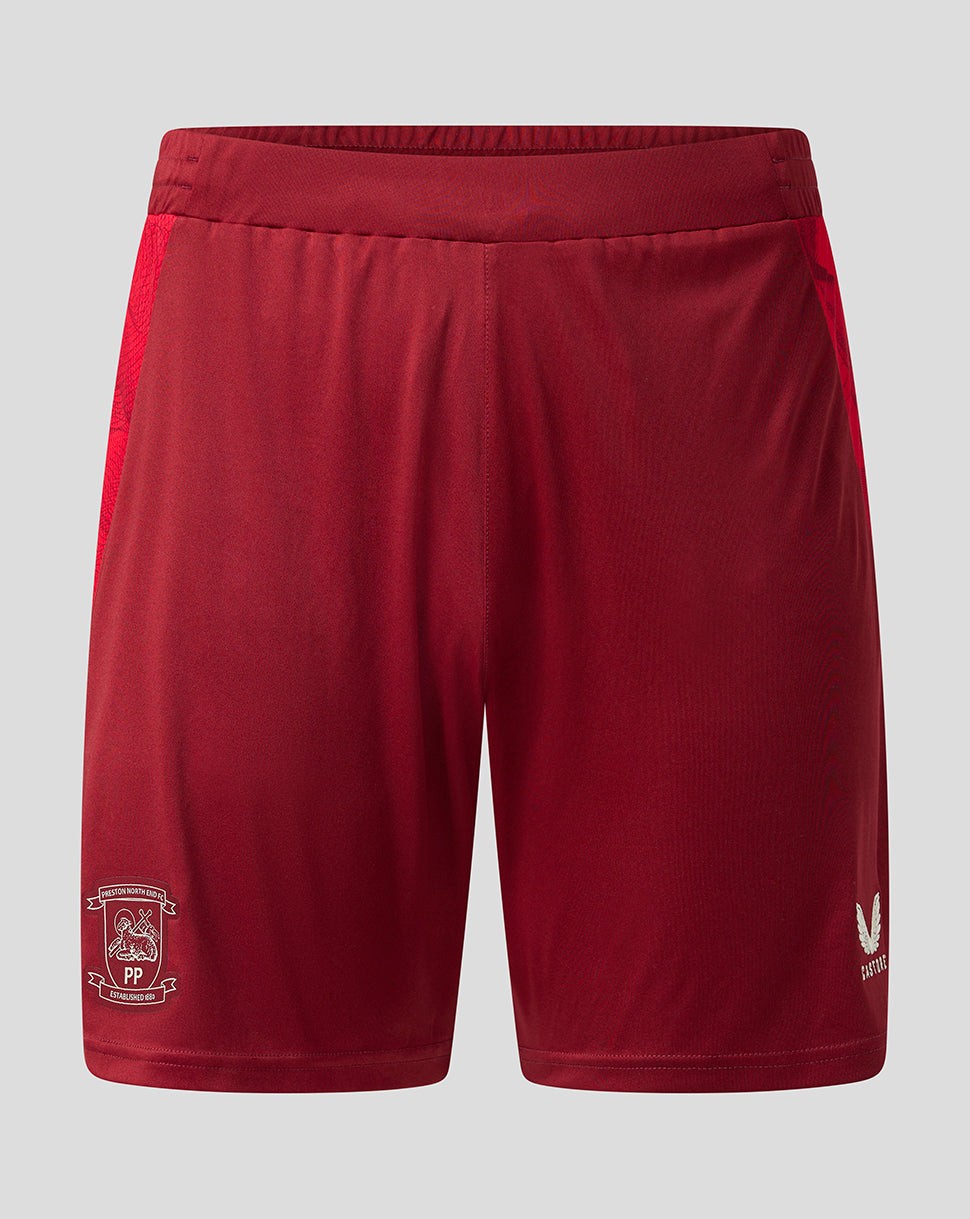 Red athletic shorts with a white club crest on the left leg and a white logo on the right leg, displayed against a light gray background.