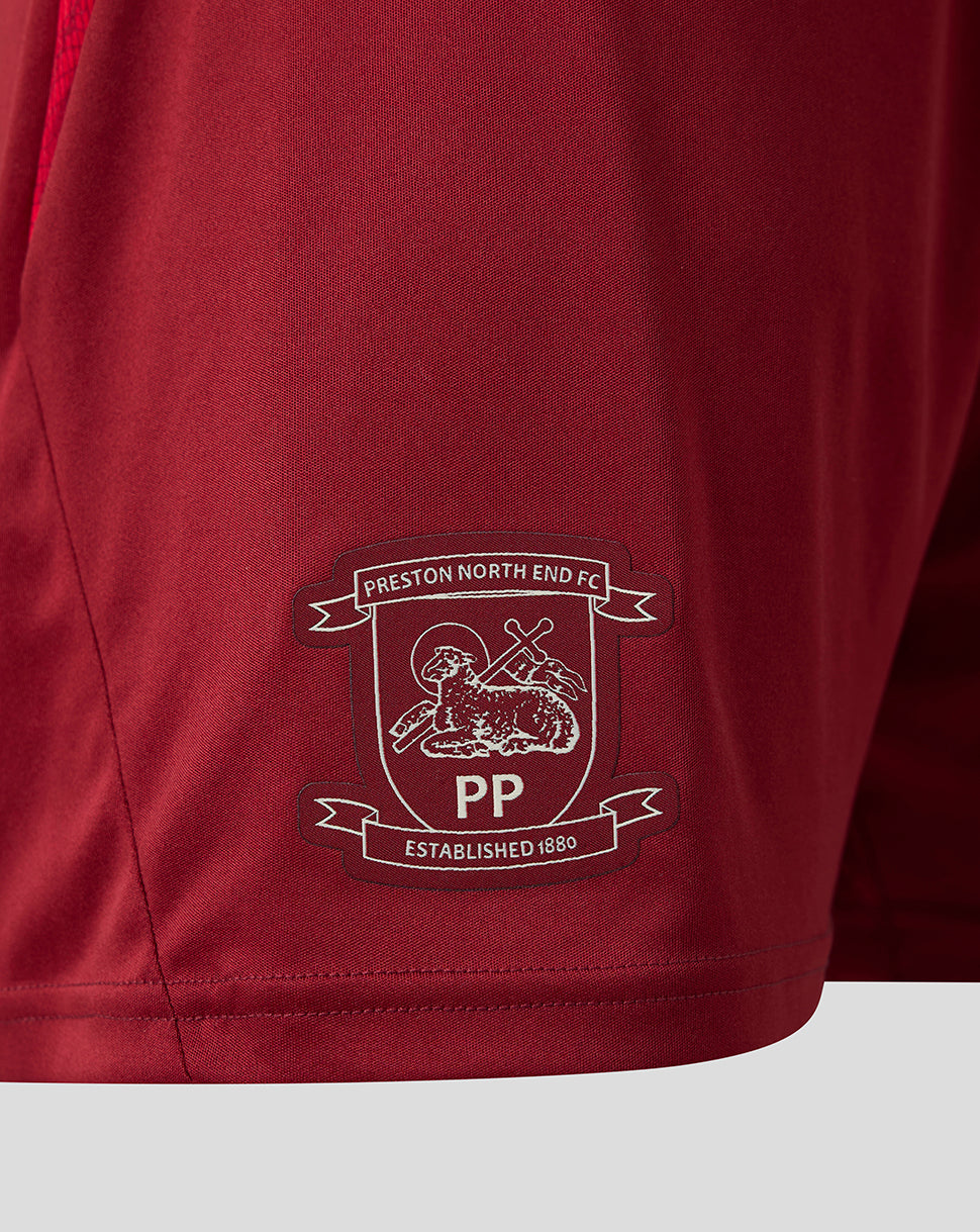 Close-up of a maroon athletic shorts leg featuring the Preston North End FC crest embroidered in white and dark red on the lower left side.