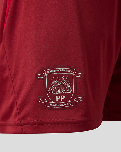Close-up of a maroon athletic shorts leg featuring the Preston North End FC crest embroidered in white and dark red on the lower left side.