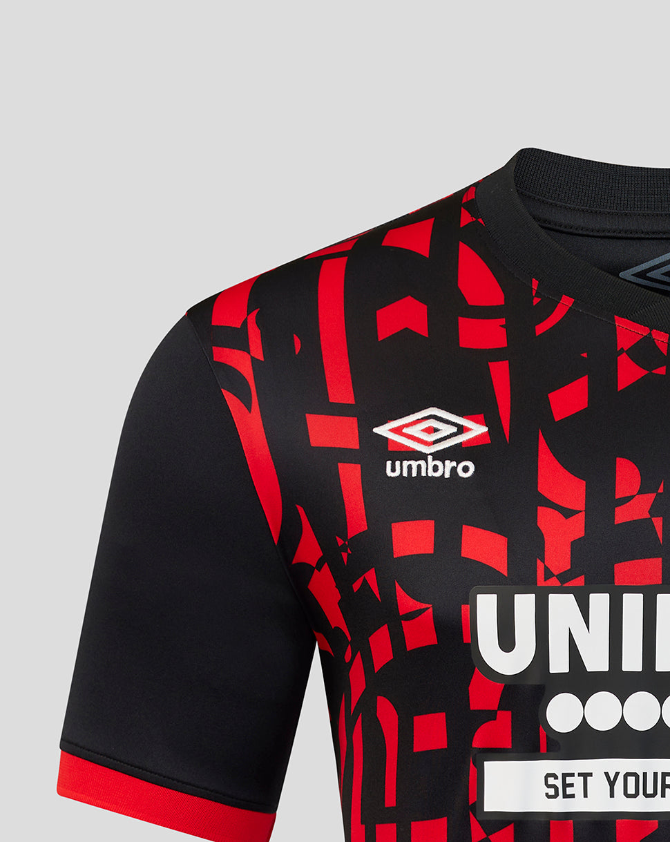 Close-up of a black and red patterned soccer jersey with the Umbro logo on the chest, set against a light gray background.