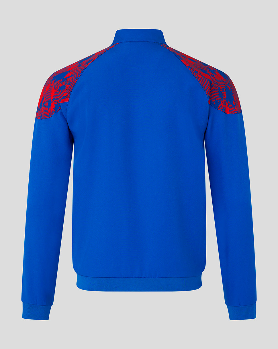 A royal blue long-sleeve track jacket shown from the back, featuring red and blue abstract patterned shoulder yokes, set against a solid light gray background.