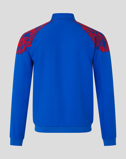 A royal blue long-sleeve track jacket shown from the back, featuring red and blue abstract patterned shoulder yokes, set against a solid light gray background.