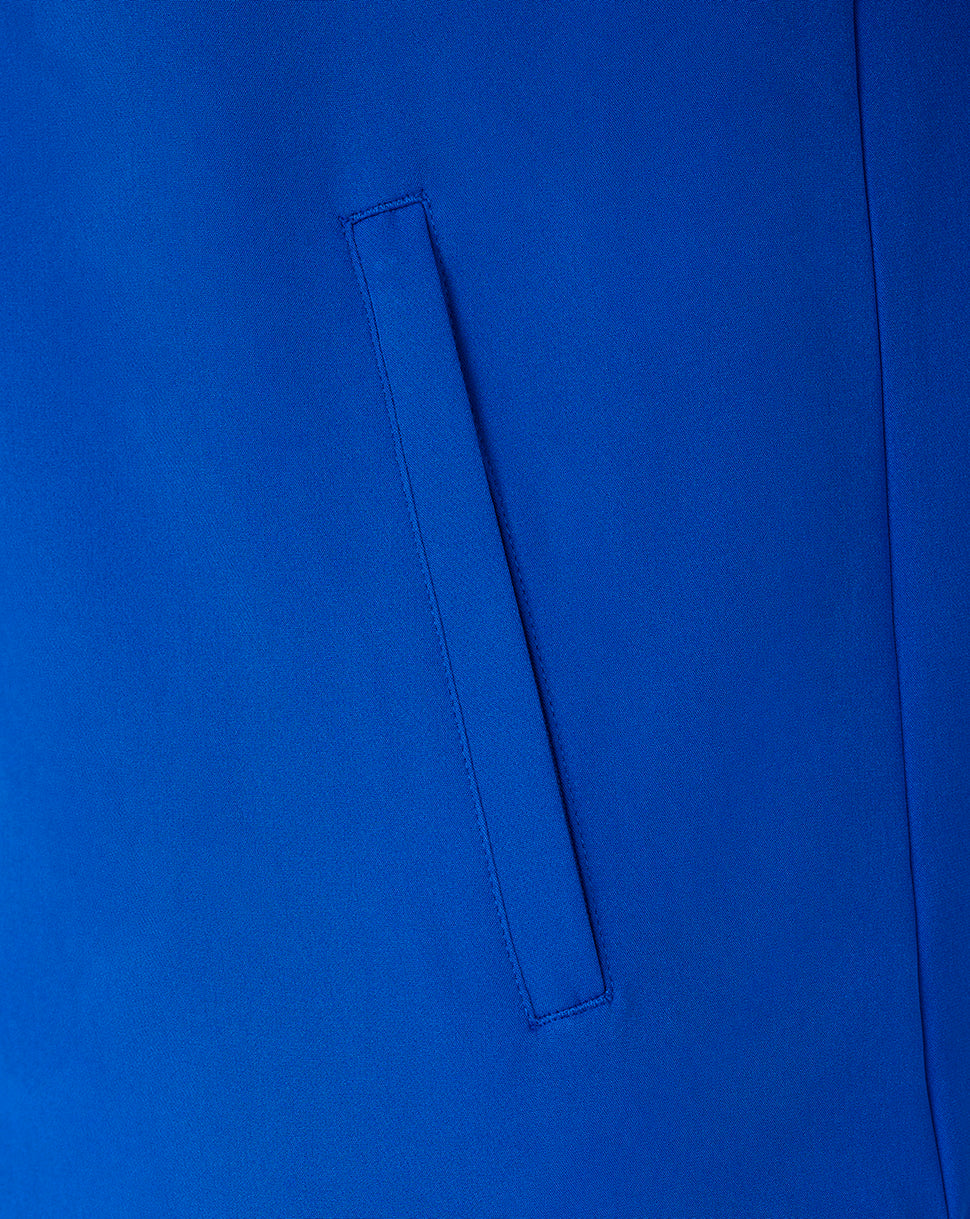 A close-up of a bright royal blue fabric surface with a vertical welt pocket stitched into it.
